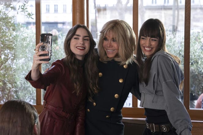 Emily prenant un selfie avec Macron et une amie dans un café, capturant l'esprit des réseaux sociaux et de la connexion sociale dans Emily in Paris.