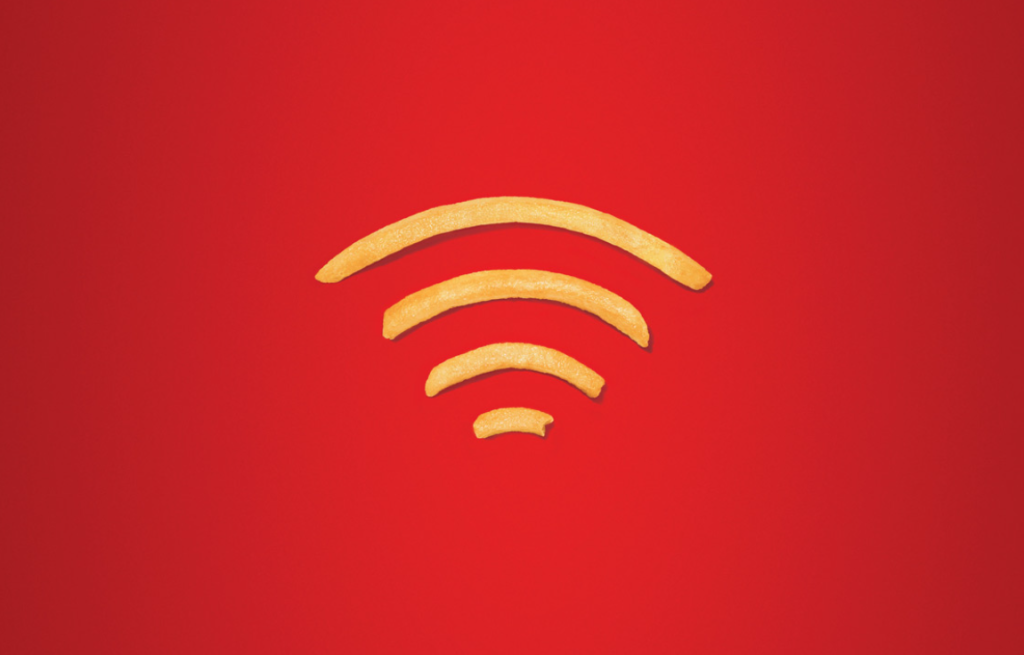 Exemple Quiet Marketing- Affiche minimaliste McDonald’s représentant des frites formant un symbole Wi-Fi sur fond rouge, avec le slogan "love free wi-fi".