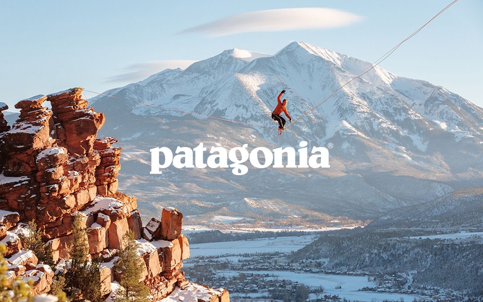 Affiche Patagonia – Slackline en montagne Affiche Patagonia montrant une personne sur une slackline entre deux falaises avec un paysage montagneux enneigé, logo Patagonia au centre.